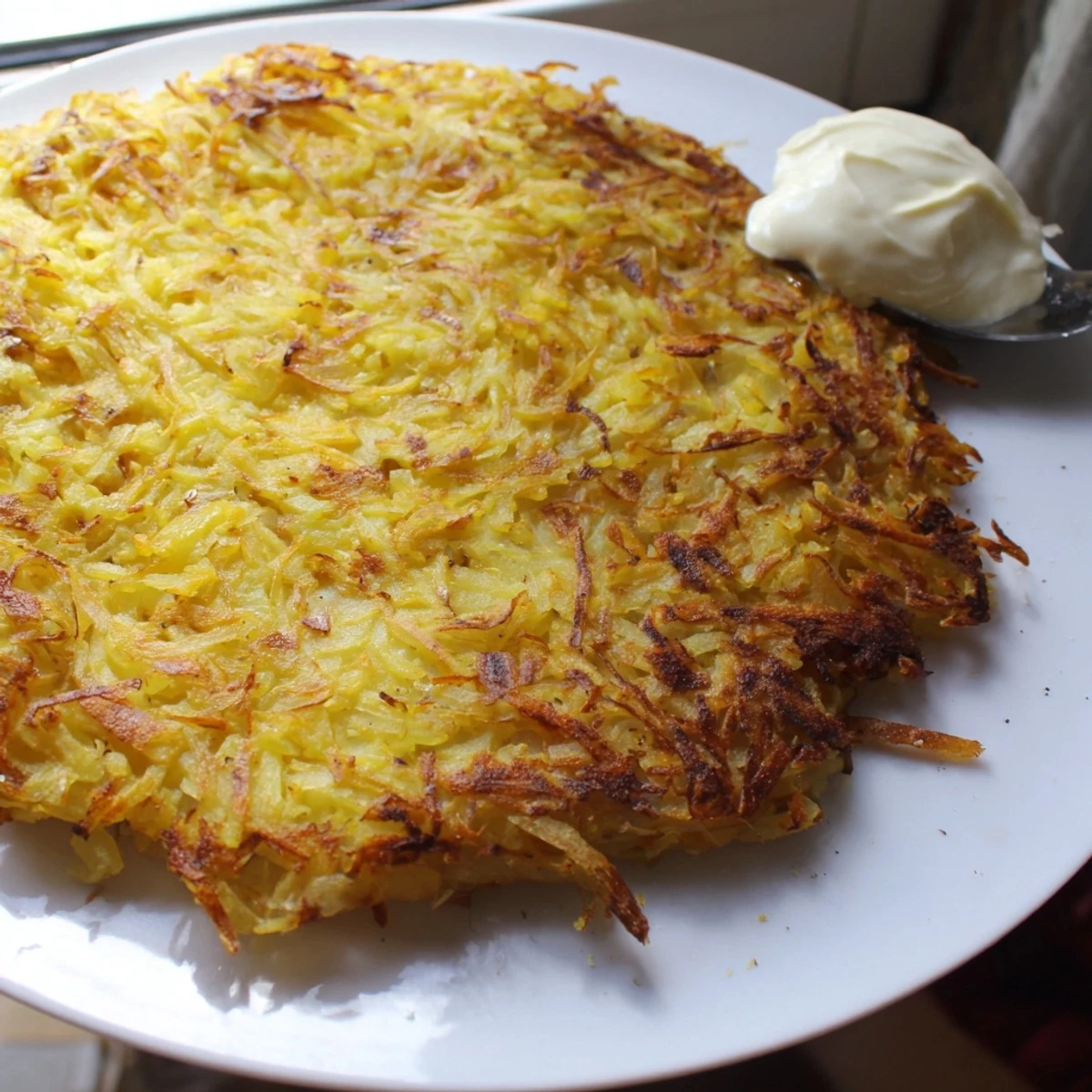 Golden-brown German potato pancakes crisped in a skillet, ready to eat alongside cool applesauce.