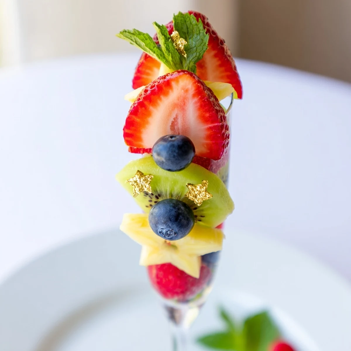 Festive champagne flute fruit garnishes with sliced strawberries, pineapple, and kiwi ready to serve.