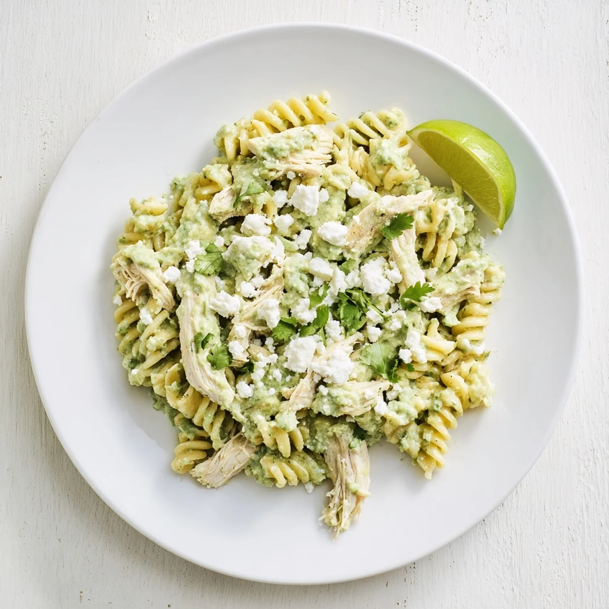 Frisch zubereitete Cilantro Lime Chicken Pasta mit glänzender Sauce, Korianderblättern und einem Stück Limette als frische Beilage.