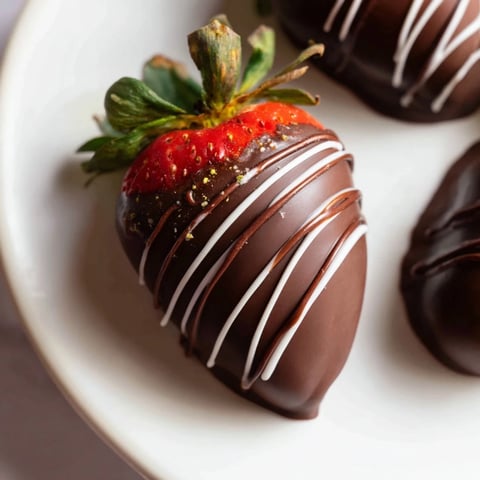 A picture of glistening dark chocolate covered strawberry dips ready to be enjoyed.