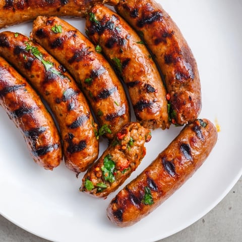 Juicy grilled Tunisian merguez sausage with visible spices, ready to eat alongside warm bread.