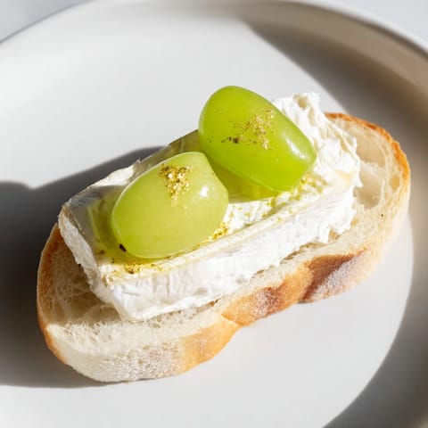 Close-up of Sparkling Champagne Toast, showcasing soaked grapes and gold glitter atop toasted bread, a festive bite.