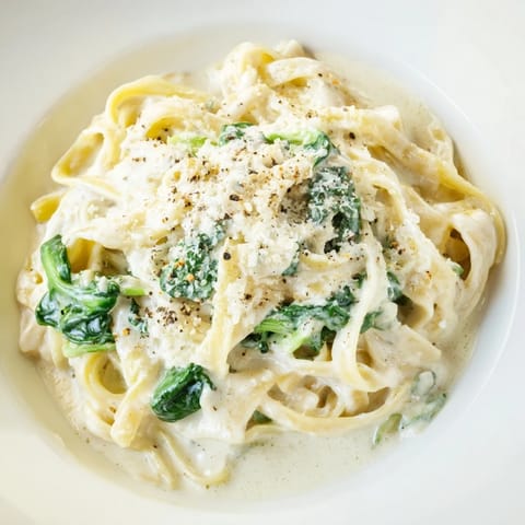 Silky, garlicky creamy spinach pasta served on a white plate, invitingly delicious.