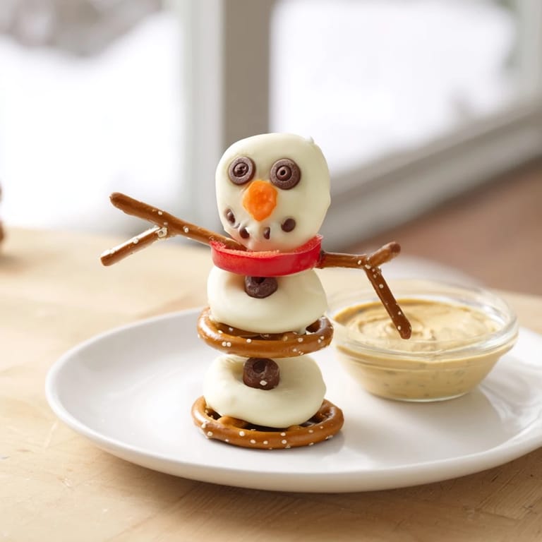 Snowman pretzel dipping platter with creamy dips, ready for a festive holiday party, visually appealing.