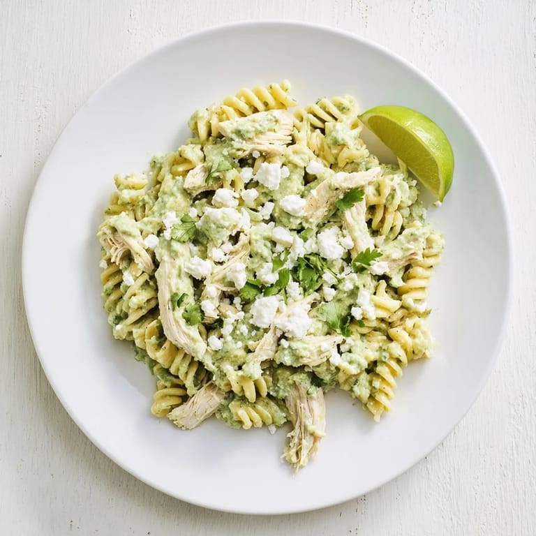 Frisch zubereitete Cilantro Lime Chicken Pasta mit glänzender Sauce, Korianderblättern und einem Stück Limette als frische Beilage.