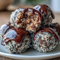 1. Schwarze Sesam-Energiekugeln mit gerösteten Samen und Haferflocken auf einem Teller, ein gesunder Snack für unterwegs.  