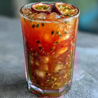 Lebendiger tropischer Sonnenaufgangs-Mocktail mit Passionsfrucht und Orange in zwei hohen Gläsern mit Orangenscheiben und Minze garniert.